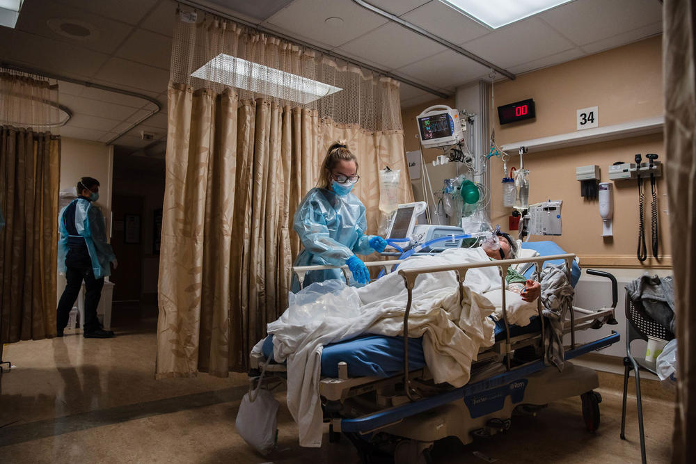 A health care worker tends to a COVID-19 patient who is using a continuous positive airway pressure machine to aid her breathing at Providence St. Mary Medical Center in Apple Valley, Calif., in January 2021.