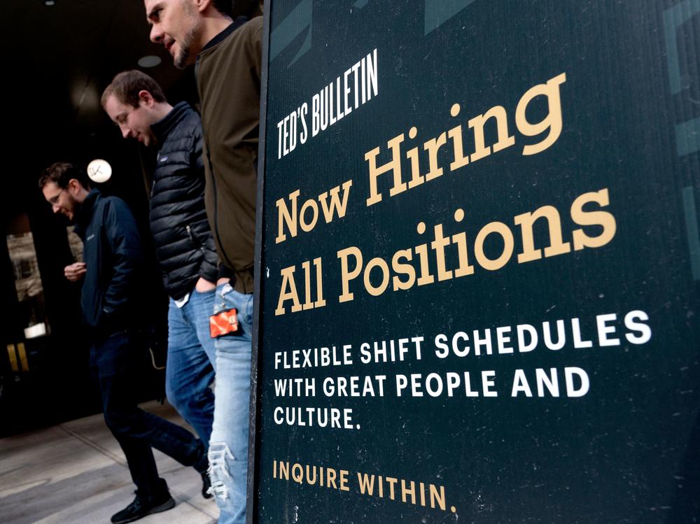 Pedestrians walk past a Now Hiring sign in Arlington, Va., on March 16.