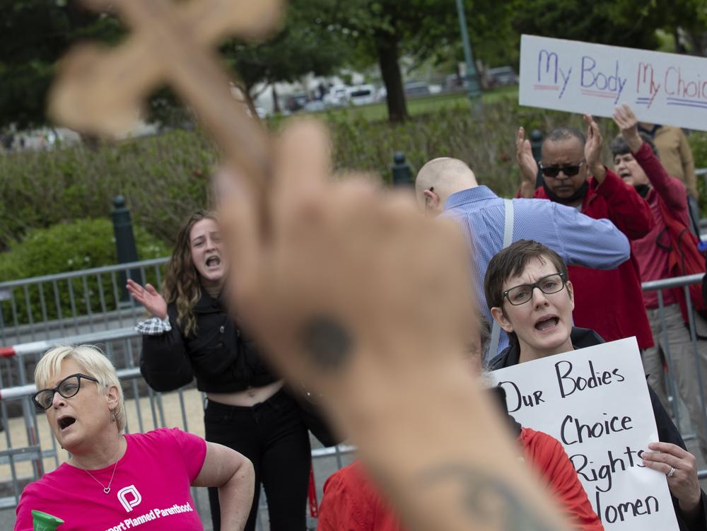 Nate Darnell holds a cross while surrounded by chanting abortion-rights demonstrators outside the U.S. Supreme Court on May 5, 2022 in Washington, D.C.