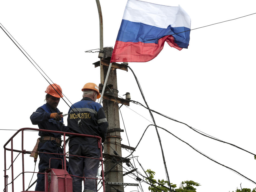 Municipal workers attach a Russian national flag to a pole preparing to celebrate 77 years of the victory in WWII in Mariupol, in territory under the government of the Donetsk People's Republic, eastern Ukraine, Thursday, May 5, 2022.