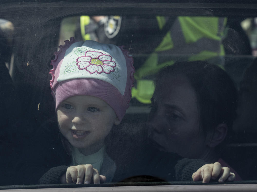 A girl looks through the window of a car as her family arrives from Mariupol at the center for displaced people in Zaporizhia, Ukraine, Thursday, May 5, 2022.