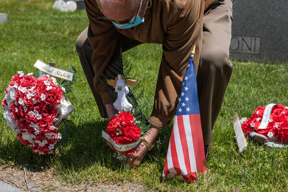 A man puts flower on his wife's grave at Calvary Cemetery on May 10, 2020, in the Queens borough of New York City. Mother's Day can be a painful time, especially for people living with loss.