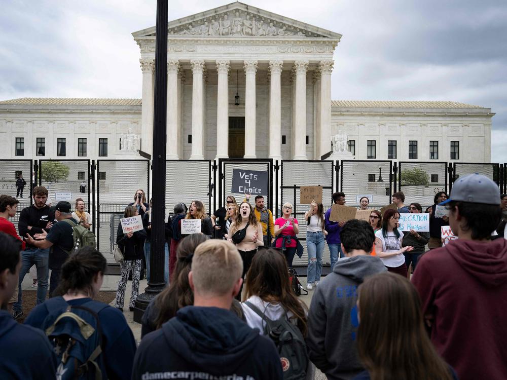 A line of anti-abortion demonstrators watch as abortion rights demonstrators chant in front of an unscalable fence that stands around the U.S. Supreme Court in Washington, D.C., on Thursday.