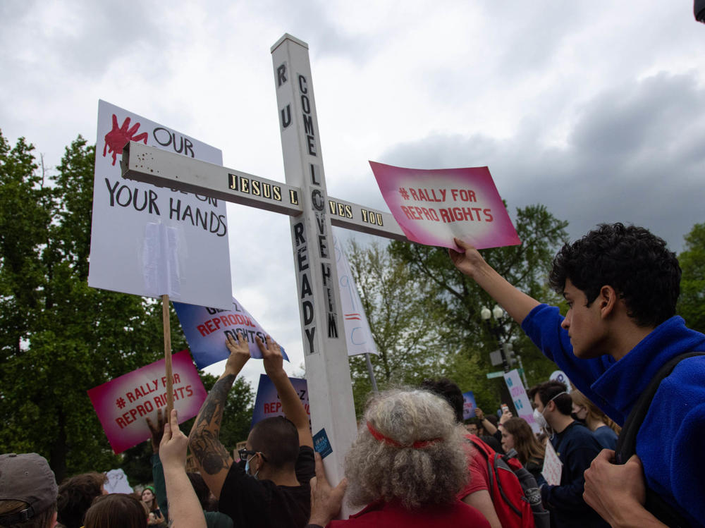 A counter-protestor holds a large cross during a youth pro-abortion rights rally outside of the Supreme Court in Washington, D.C., on May 5, following the leak of a draft Supreme Court opinion to overturn <em>Roe v. Wade</em>.