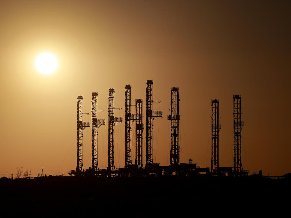 Drilling rigs sit unused on a lot located in the Permian Basin area in Odessa, Texas, on March 13. Oil companies are boosting production, but at a measured pace.