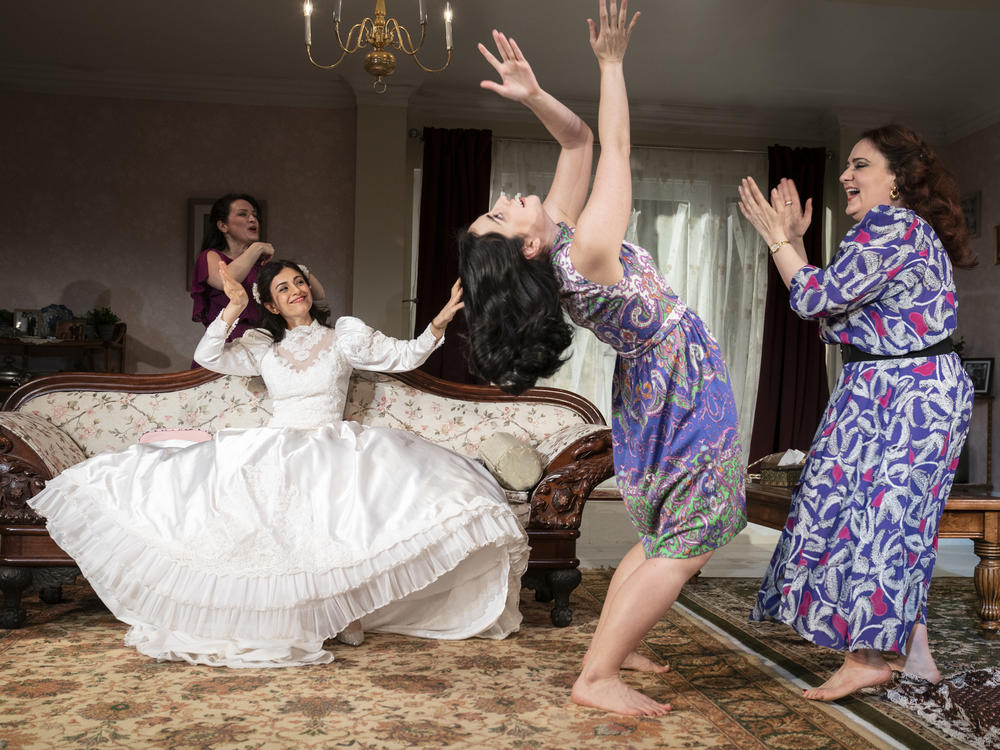 Marjan Neshat (in white dress), Roxanna Hope Radja (behind couch), Nikki Massoud and Artemis Pebdani in <em>Wish You Were Here</em>.