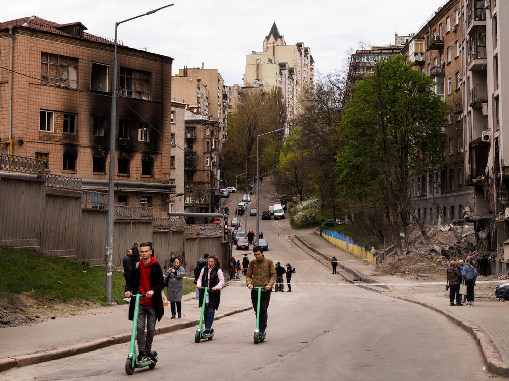 People ride scooters in Kyiv past buildings that were damaged by Russian a missile strike last week.
