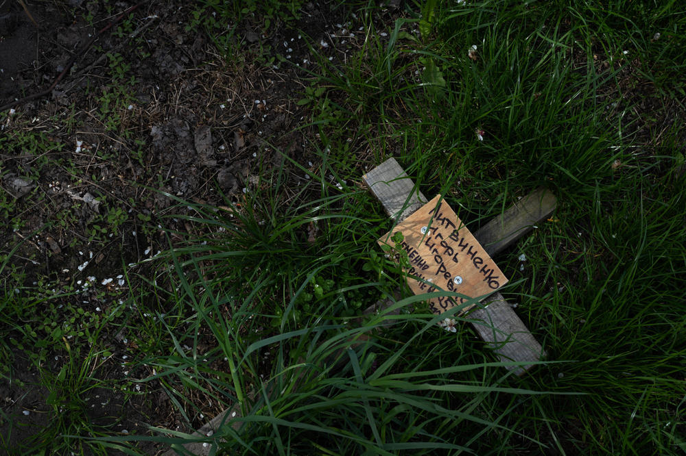 A temporary grave marker lies in the grass outside a residential building in Bucha, a suburb of Kyiv. The body was removed from the grave after Russian forces withdrew from the area.