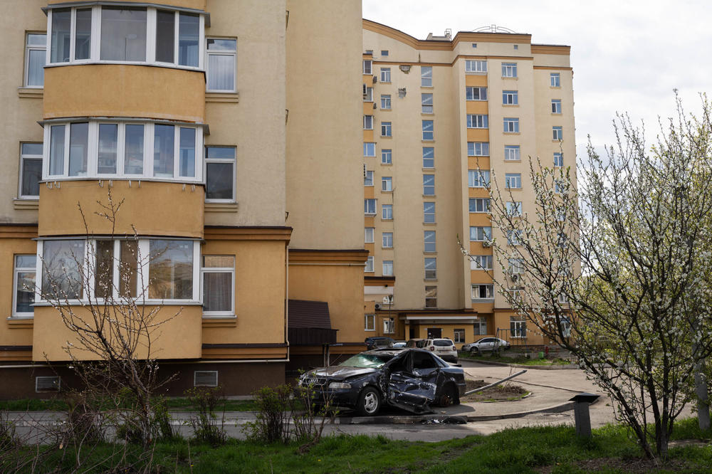 A wrecked car sits on the side of a road in an area of Bucha, a suburb of Kyiv, that has begun to be cleaned up. The area's residents say the parking lot was previously filled with many more smashed cars.