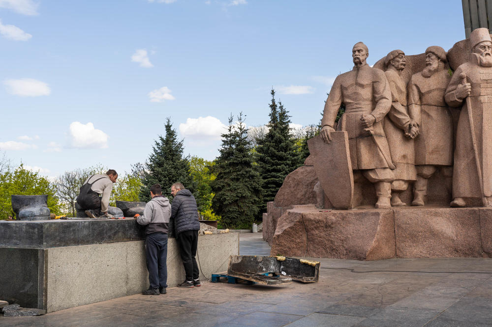 Men figure out how to dismantle the last bits of a monument in Kyiv commemorating the friendship between Ukraine and Russia.