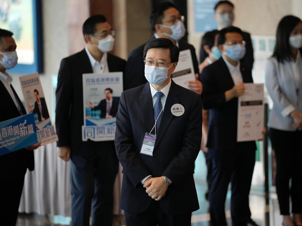 John Lee, former No. 2 official in Hong Kong, and the only candidate for the city's top job, waits for the election committee members outside a polling station for the chief executive election in Hong Kong, Sunday, May 8, 2022.