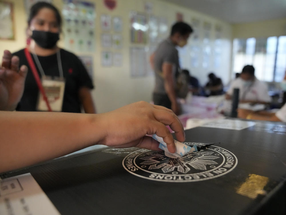 An election worker places a voting receipt inside a box at a polling center Monday in Quezon City, Philippines.