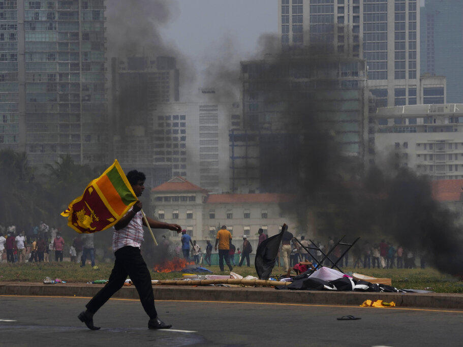 A Sri Lankan government supporter carries a national flag after attacking the anti-government demonstrators outside the president's office in Colombo, Sri Lanka, on Monday.