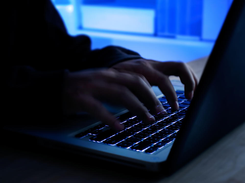 A computer programmer prints a code on a laptop keyboard.
