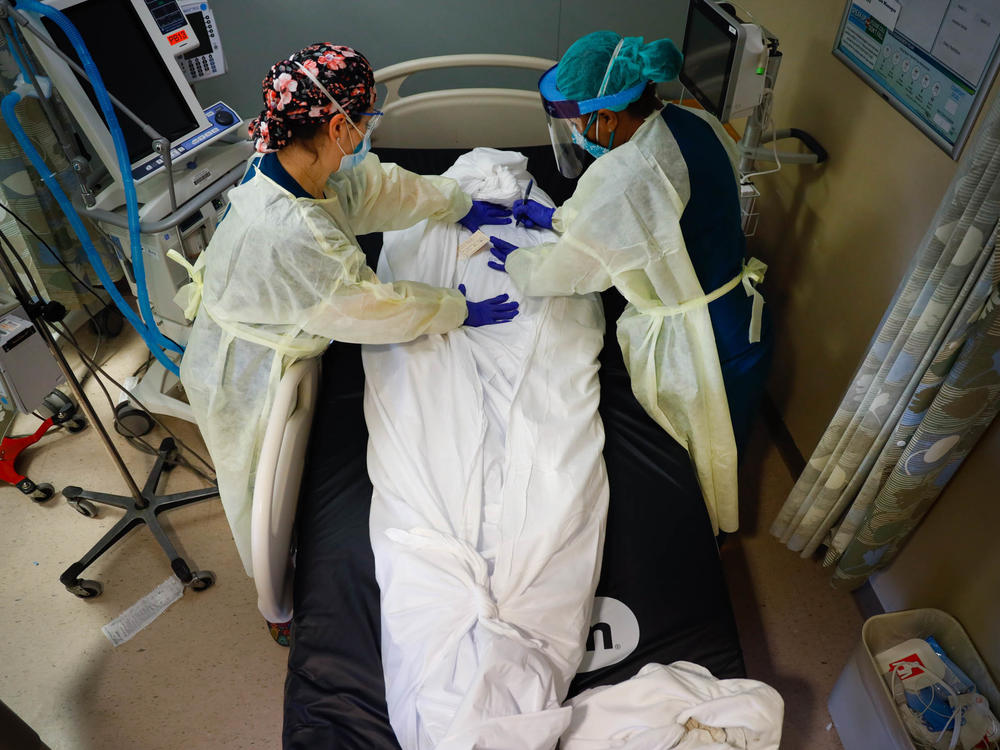 Nurse educator Katie Demelis and nurse manager Nydia White wrap the the body of a patient who died of COVID-19 at Mount Sinai South Nassau hospital in Oceanside, N.Y., on April 15, 2020.