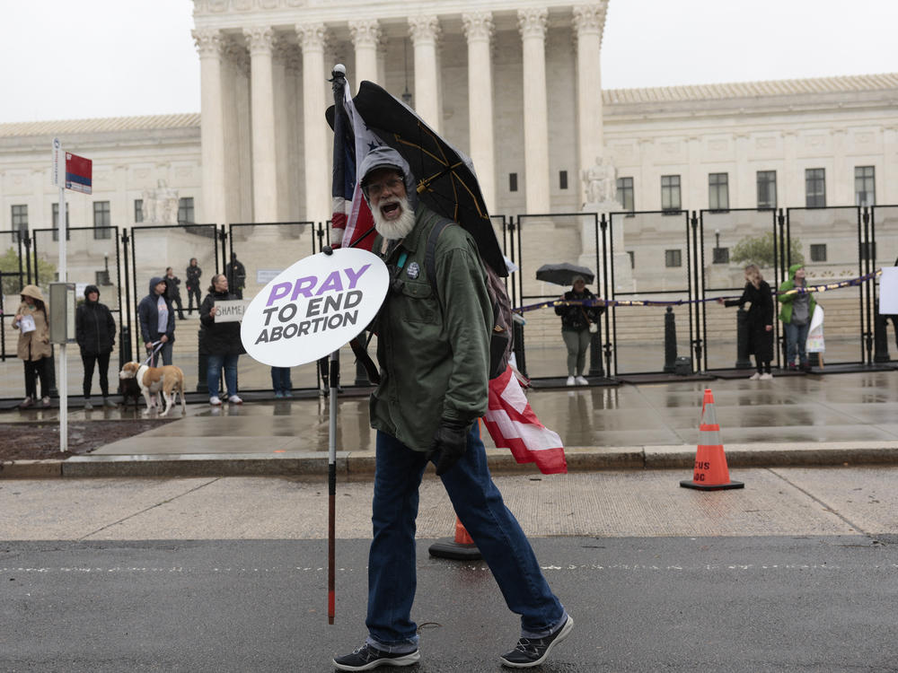 An anti-abortion protester walks past as abortion-rights activists participate in a demonstration in front of the Supreme Court on Saturday.