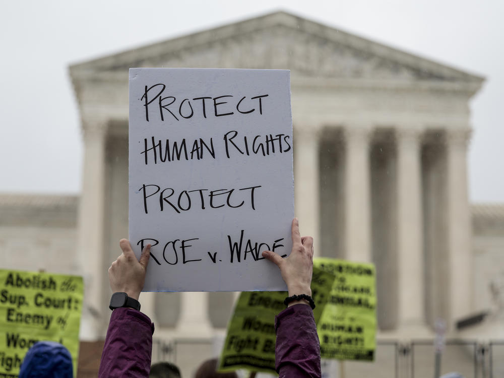 An abortion-rights protester holds up a sign during a demonstration in front of the Supreme Court on Saturday in Washington, D.C. Less than a week since the leaked draft of the Court's potential decision to overturn <em>Roe v. Wade,</em> protesters on both sides of the abortion debate continue to demonstrate in front of the building which has been fortified by a temporary fence.