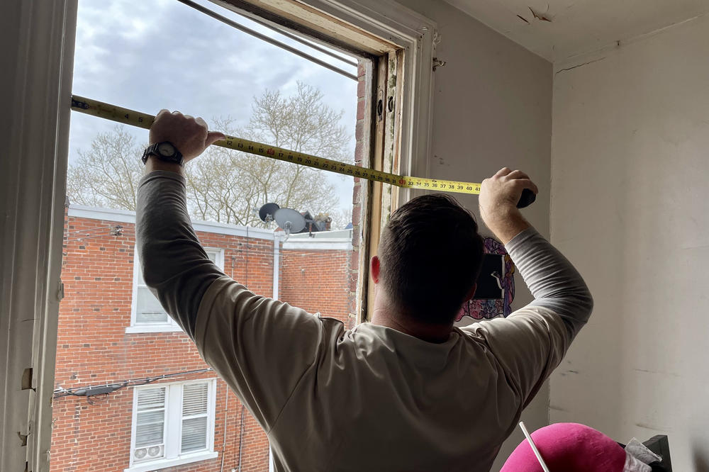 A carpenter from PC Weatherizing prepares to install a new, double-glazed window in Rezephyr Young's house, as a part of a holistic home repair program called Built to Last.