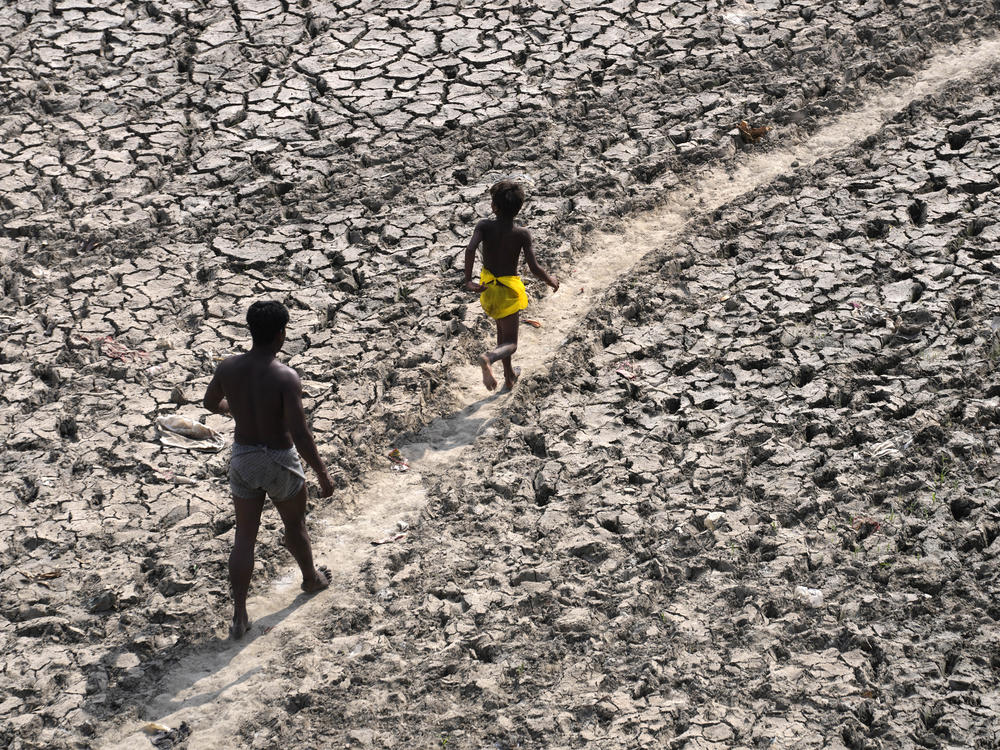 A man and a boy walk across the almost dried up bed of river Yamuna following hot weather in New Delhi, India, May 2, 2022.