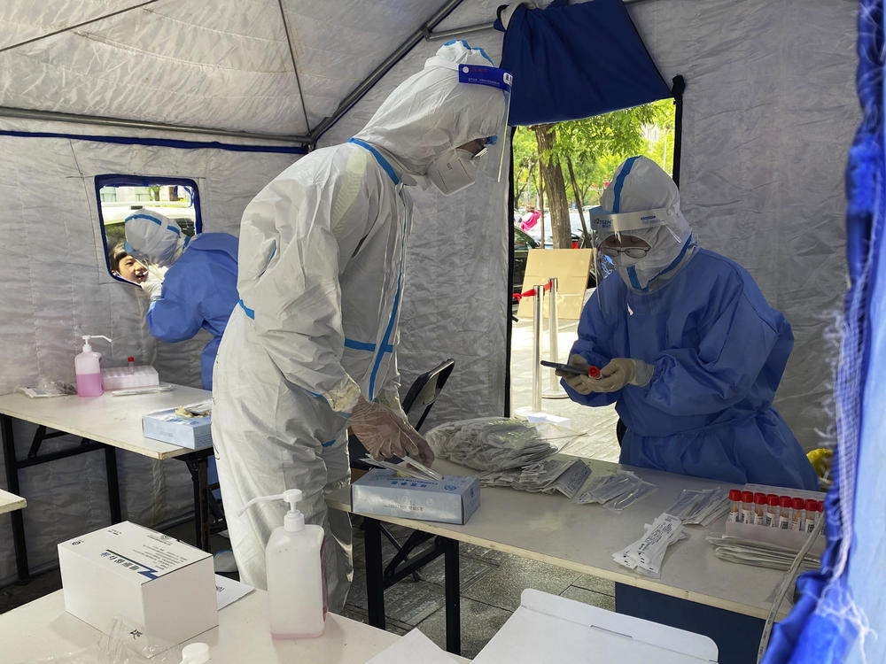 Workers in protective overalls conduct mass COVID testing for residents on May 11, 2022, in Beijing.