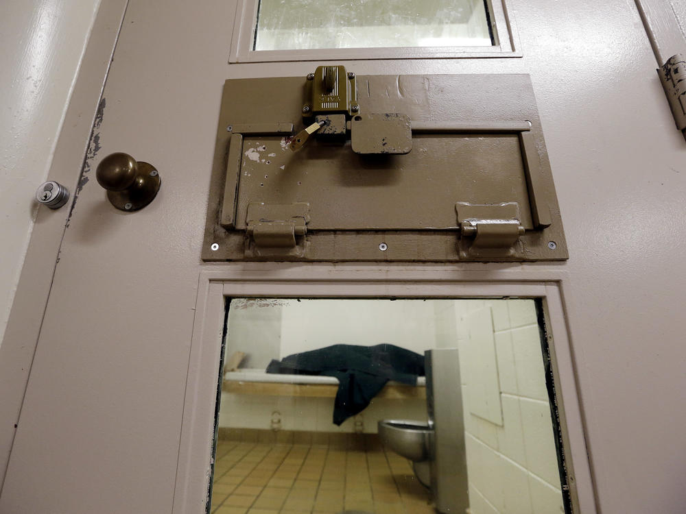 An inmate huddles under a heavy blanket on a bunk in the psychiatric unit of the Pierce County jail in Tacoma, Wash. in 2014.