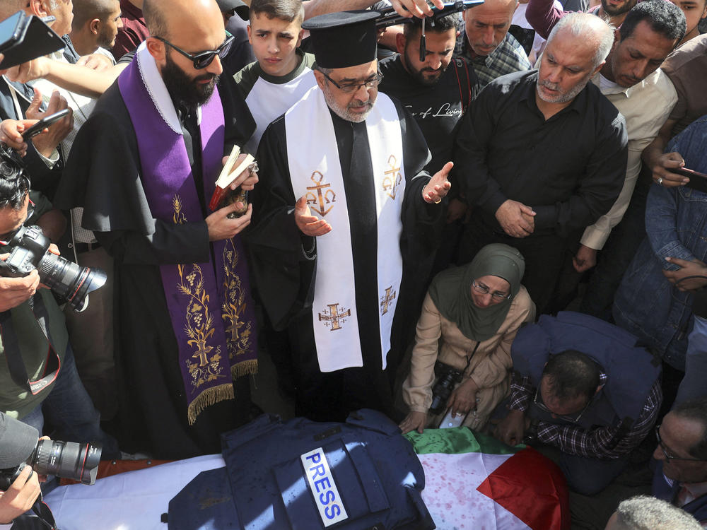 Priests and friends mourn over the body of veteran Al Jazeera Palestinian journalist Shireen Abu Akleh Wednesday, after she was shot dead as she covered an Israeli army raid on the West Bank's Jenin refugee camp.