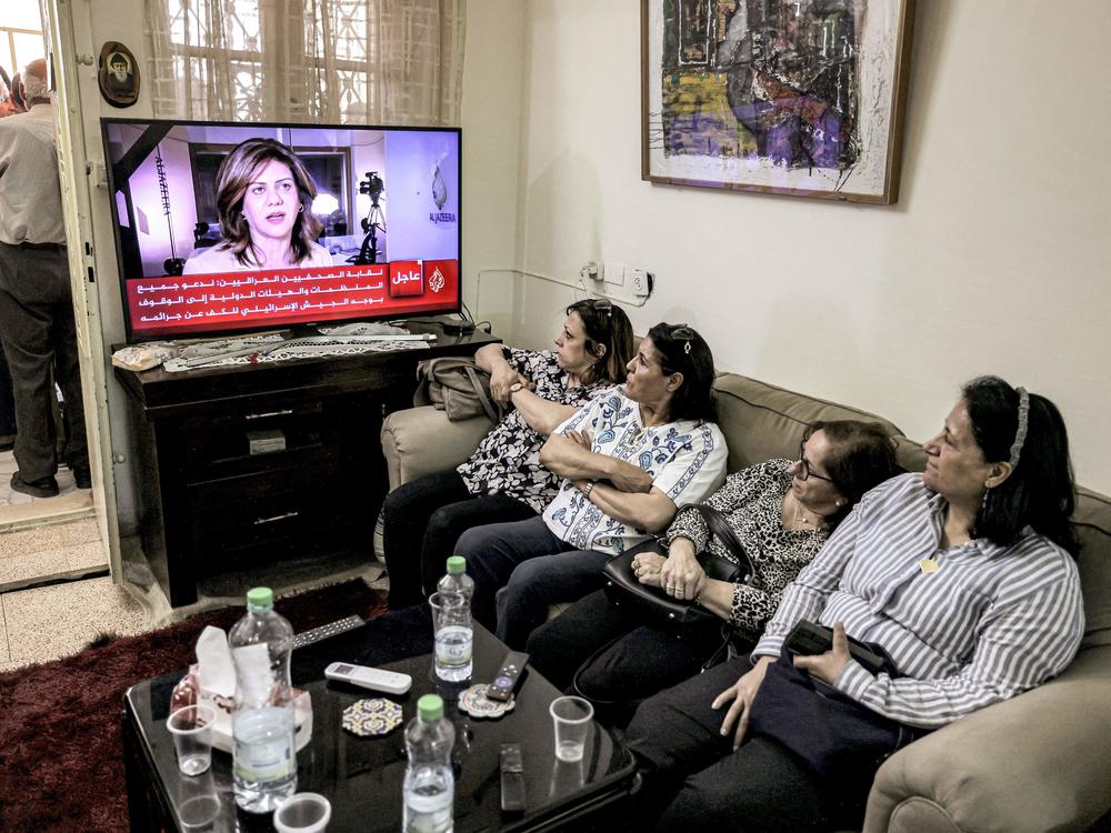 Women watch an Al Jazeera obituary report on TV at the family home of Al Jazeera journalist Shireen Abu Akleh in the Palestinian neighborhood of Beit Hanina in Israeli-occupied east Jerusalem on Wednesday, after she was killed as she covered an Israeli army raid on Jenin refugee camp in the occupied West Bank.