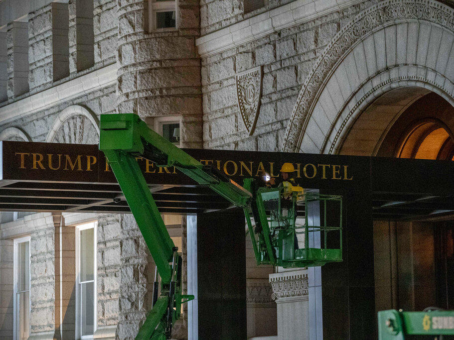 A worker removes the signage for the Trump International Hotel on Wednesday, in Washington.
