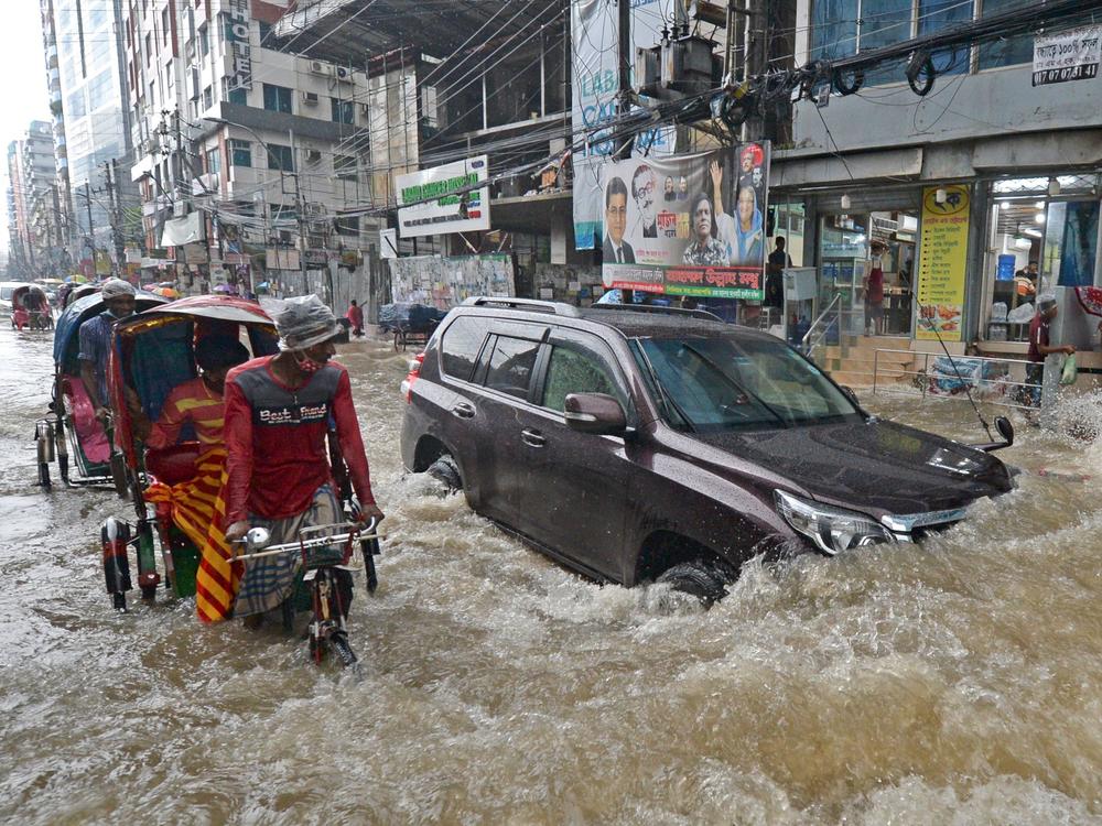 Commuters make their way through a water-logged street after a heavy downpour in Dhaka. Bangladesh is one of many countries struggling to protect residents from the effects of climate change.