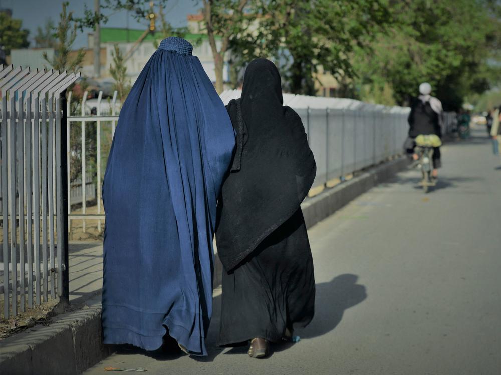 Women wearing a burqa (left) and a niqab (right) walk along a street in Kabul on May 7.