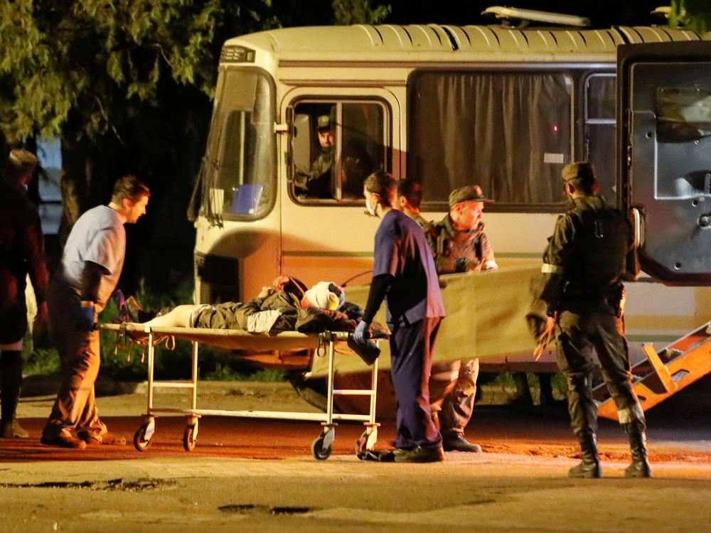 A wounded service member of the Ukrainian forces from the besieged Azovstal steel mill in Mariupol is transported out of a bus on a stretcher under escort of pro-Russian fighters, upon arrival in Novoazovsk, Ukraine, on Monday.