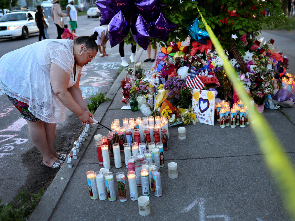 On Sunday, a woman lights a candle at a makeshift memorial to the victims of Saturday's mass shooting at Tops market in Buffalo, N.Y.