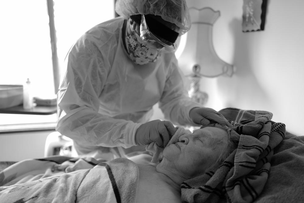 Delores Jetton carefully bathes Elvy Kaik during a hospice visit on April 23, 2020. Because their work is so hands-on, Delores and other home health care workers on Whidbey Island wear extensive gear and take extra precautions to minimize COVID risk.