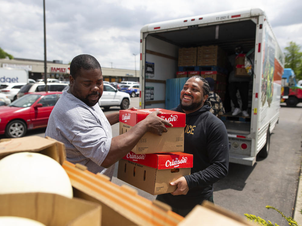 Pastor Andre Kamoche, left, and Greg Jackson, with Rehoboth House of Prayer, help unload a truck of fresh produce to be given out to people affected by the Tops closure on Tuesday in Buffalo, N.Y.