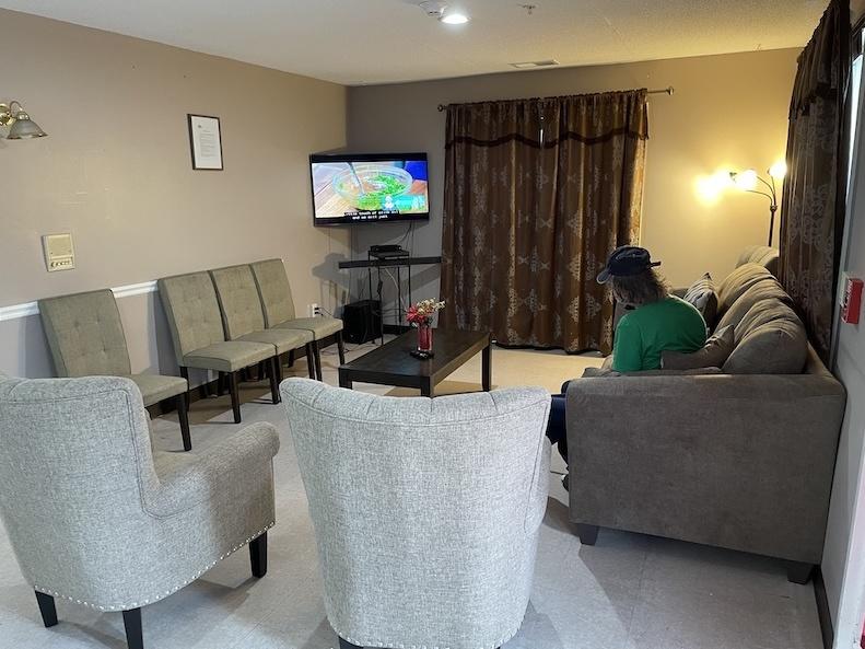A resident watches a cooking show in the living room at Hope Has a Home medical respite in Washington, D.C.