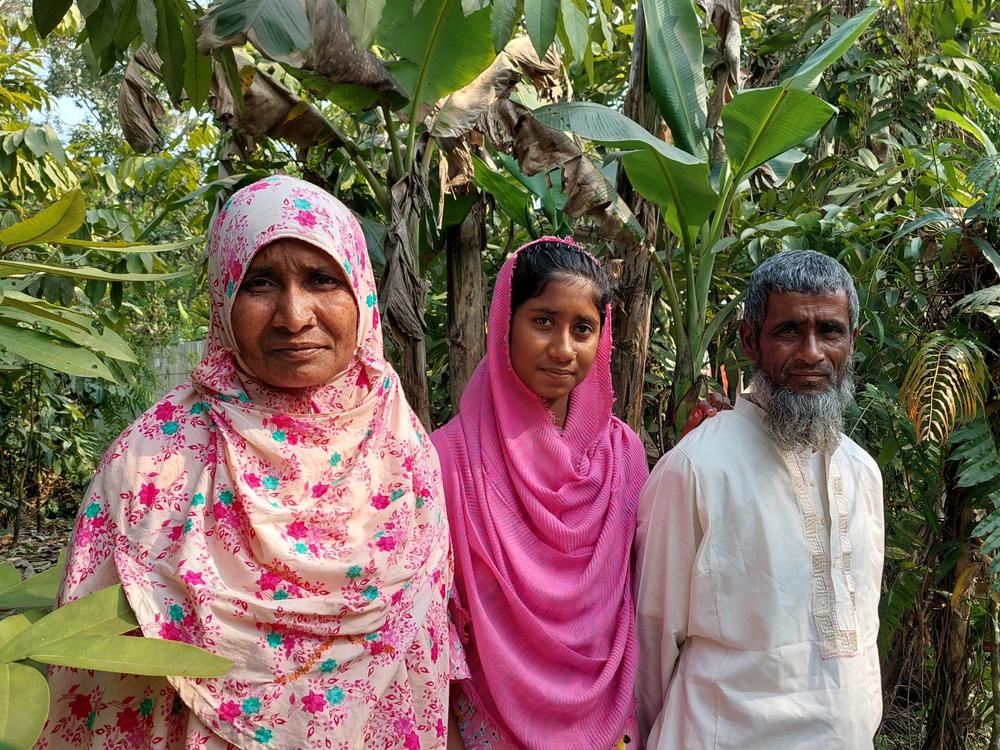 Rahima Banu outside her home with her daughter and husband.