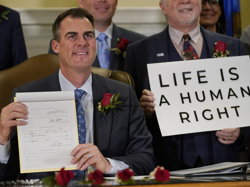 Oklahoma Gov. Kevin Stitt poses for a photo with the bill he signed, making it a felony to perform an abortion, punishable by up to 10 years in prison, on April 12, 2022, in Oklahoma City, following a bill signing ceremony.
