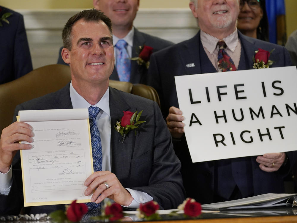 Oklahoma Gov. Kevin Stitt poses for a photo with the bill he signed, making it a felony to perform an abortion, punishable by up to 10 years in prison, on April 12, 2022, in Oklahoma City, following a bill signing ceremony.