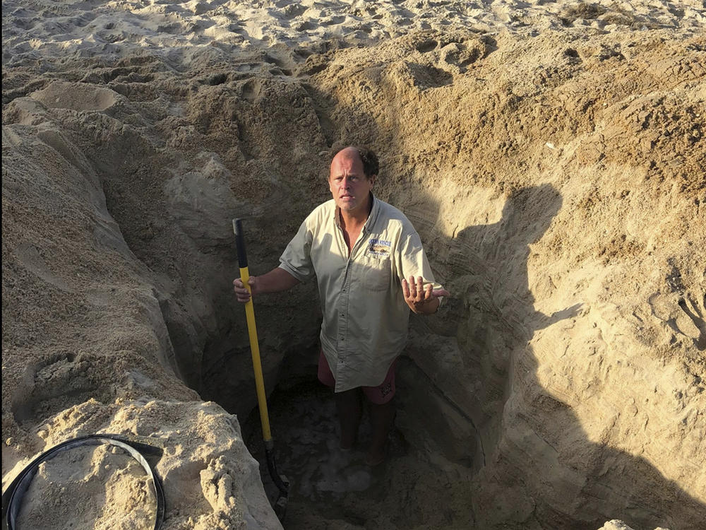 David Elder, ocean rescue supervisor for Kill Devil Hills, N.C, stands in a hole he estimates to be 7 feet deep on Sunday. The town on North Carolina's Outer Banks has issued a plea to beachgoers about the dangers of digging holes on the beach.