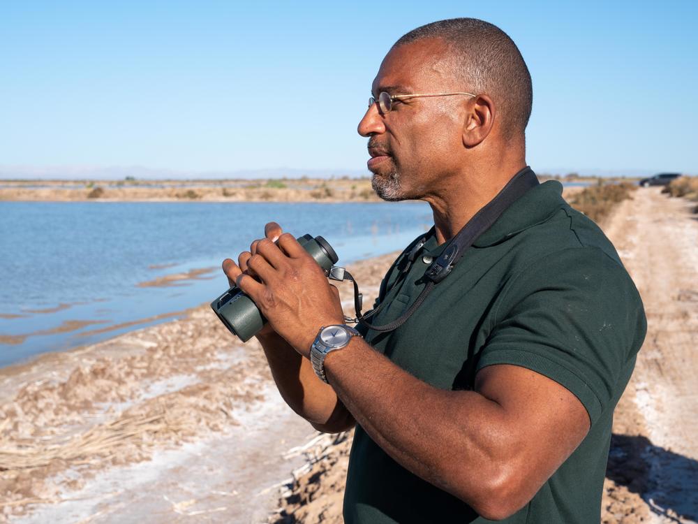 Christian Cooper watches distant shorebirds at the Sonny Bono Salton Sea National Wildlife Refuge in California. The National Geographic channel has announced that Cooper will host a series called <em>Extraordinary Birder</em>. Cooper was in the spotlight after a woman in New York City's Central Park called the police and falsely accused him of threatening her in May 2020.