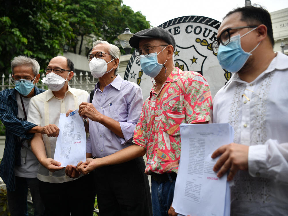 Martial law victims including former lawmaker Satur Ocampo (third from left) and their lawyers headed by Howard Calleja (second from left), show documents after filing a petition with the supreme Court in Manila on Wednesday seeking the disqualification of presumptive president Ferdinand Marcos Jr.