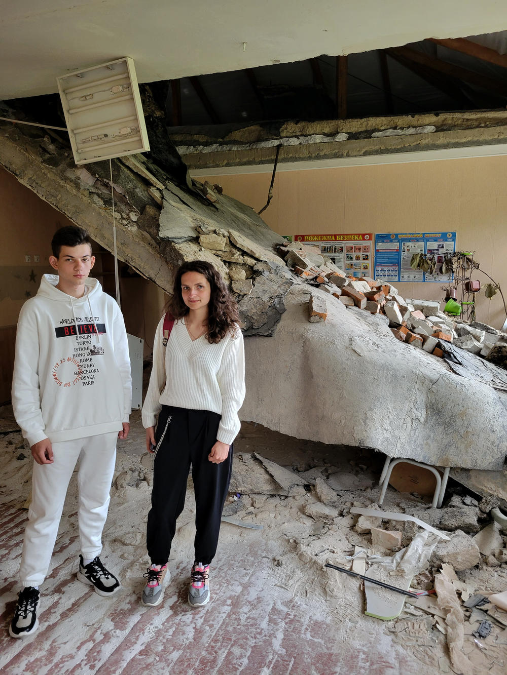 Vova Hrabovenko, 17, and his teacher Viktoria Timoshenko in what's left of her biology classroom after Russian shelling. 