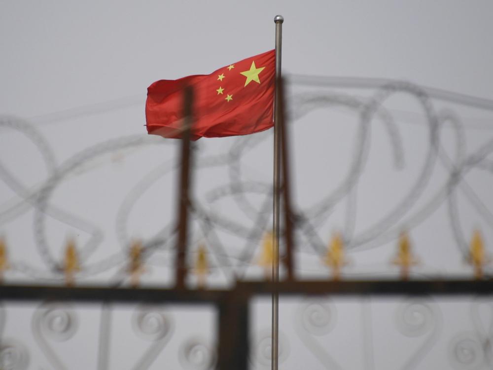 The Chinese flag is visible behind razor wire at a housing compound in Yangisar, south of Kashgar, in China's western Xinjiang region.