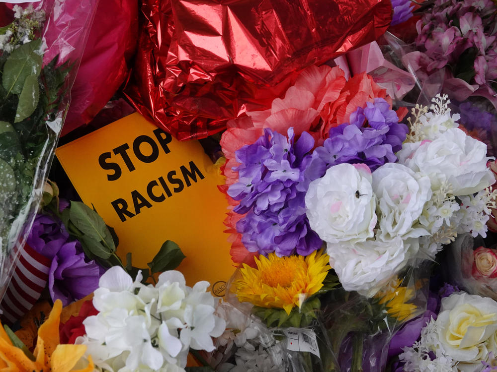 Flowers, candles and mementoes are left at a makeshift memorial outside the Tops market on May 18, 2022 in Buffalo, New York. Police say the shooting that killed 10 and wounded three is being investigated as a racially motivated hate crime.