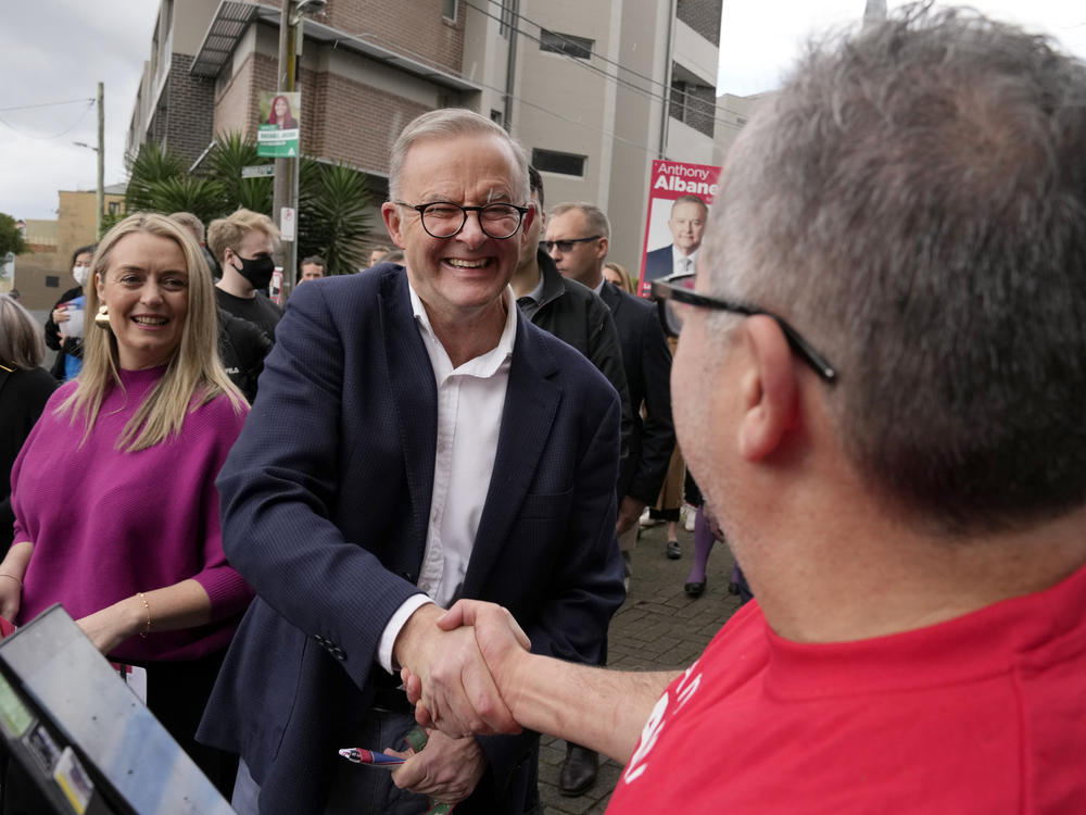 Labor Party leader Anthony Albanese (center) shakes hands with a voter as he and his partner Jodie Haydon (left) arrive at a polling place to cast their ballots in Sydney, Australia, on Saturday.
