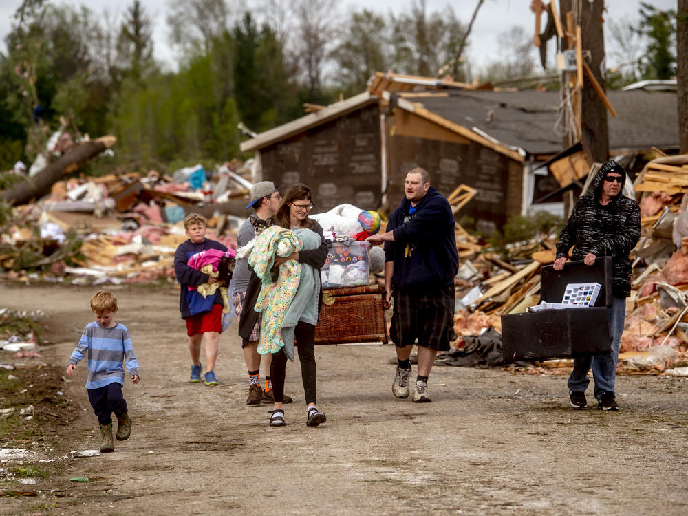 Resident Stephanie Kerwin, center, holds her baby Octavius in one arm and dog Pixie in the other as she and her family carry what they could salvage from her home in Nottingham Forest Mobile Home Park on Saturday in Gaylord, Mich., following a tornado the day before.