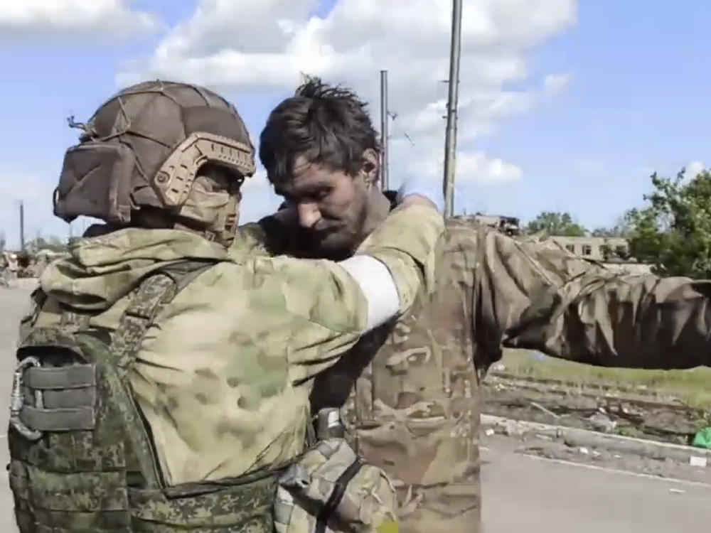 In this photo taken from video released by the Russian Defense Ministry on Friday, May 20, 2022, a Russian serviceman frisks a Ukrainian serviceman after they leaved the besieged Azovstal steel plant in Mariupol, in territory under the government of the Donetsk People's Republic, eastern Ukraine.