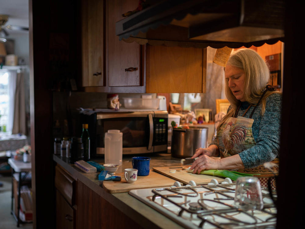 Nancy Rose, right, who contracted COVID-19 in 2021 and continues to exhibit long-haul symptoms including brain fog and fatigue, cooks for her mother, Amy Russell, left, at their home, Tuesday, Jan. 25, 2022, in Port Jefferson, N.Y. Researchers are trying to understand what causes these long COVID symptoms.