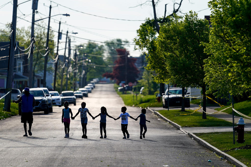 Children walk hand in hand in a street near the scene of a shooting from the day before at a supermarket in Buffalo, N.Y., on Sunday, May 15, 2022.