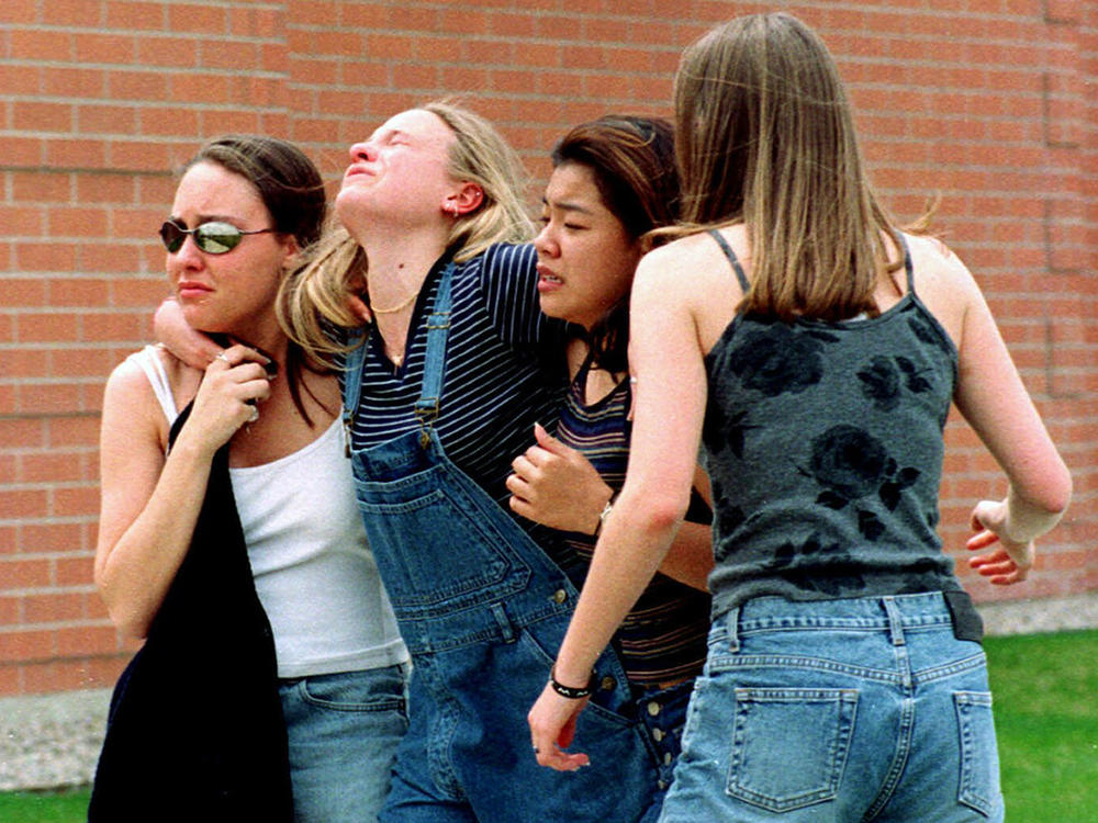 In this April 20, 1999, file photo, women head to a library near Columbine High School where students and faculty members were evacuated after two gunmen went on a shooting rampage in the school in the Denver suburb of Littleton, Colo.
